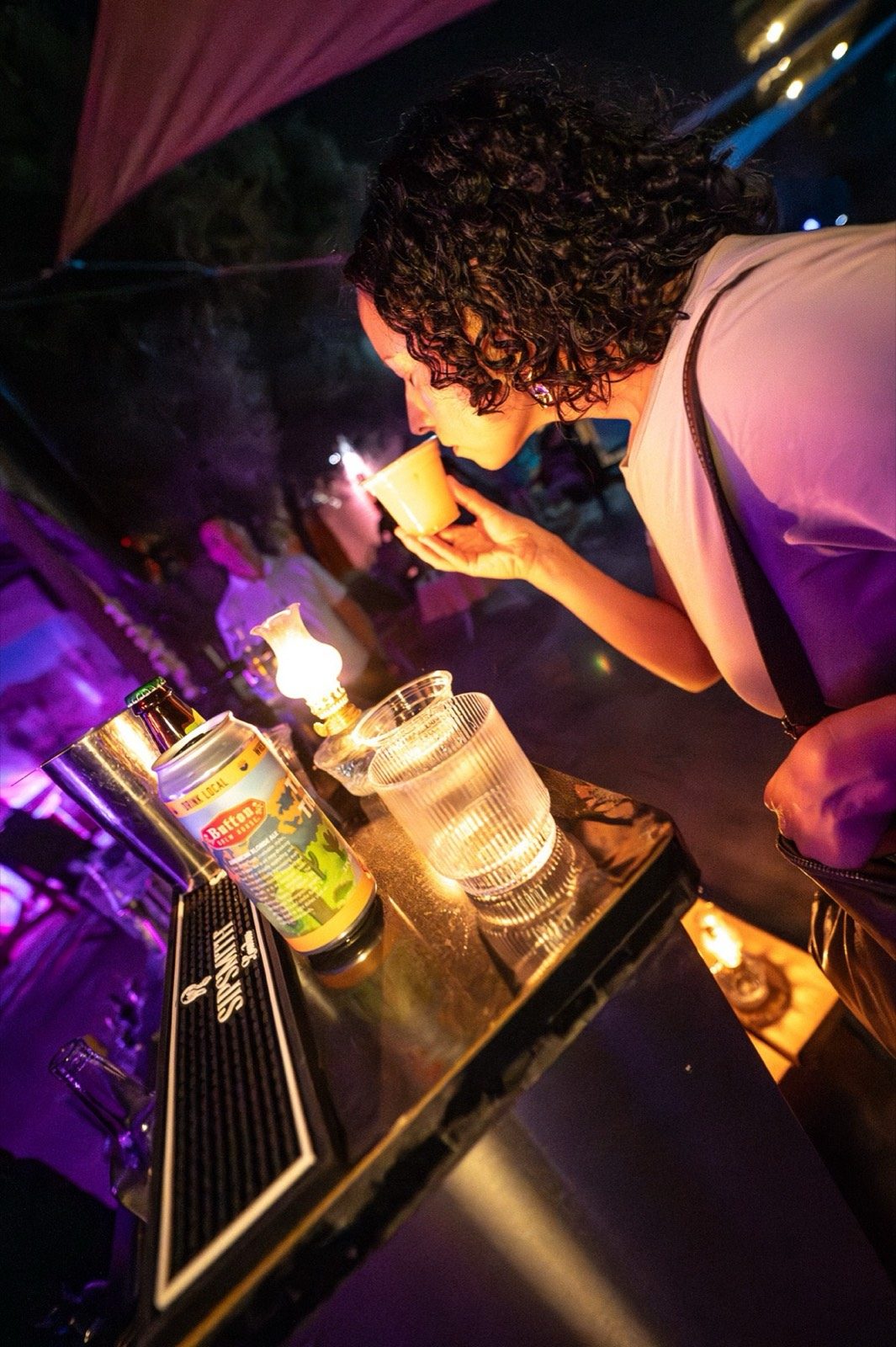A guest tasting a drink at the Brandylion bar beside a lit oil lamp