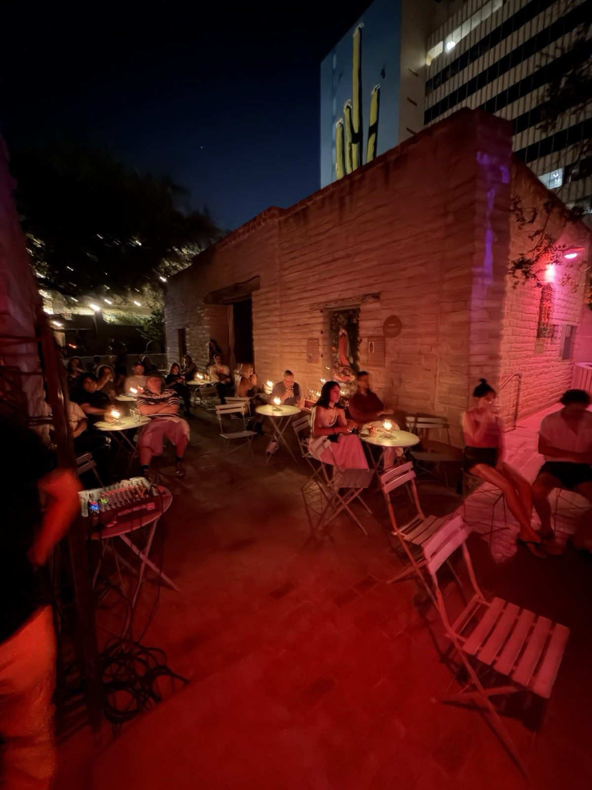 Courtyard tables set by candlelight at night, the adobe walls washed warm red