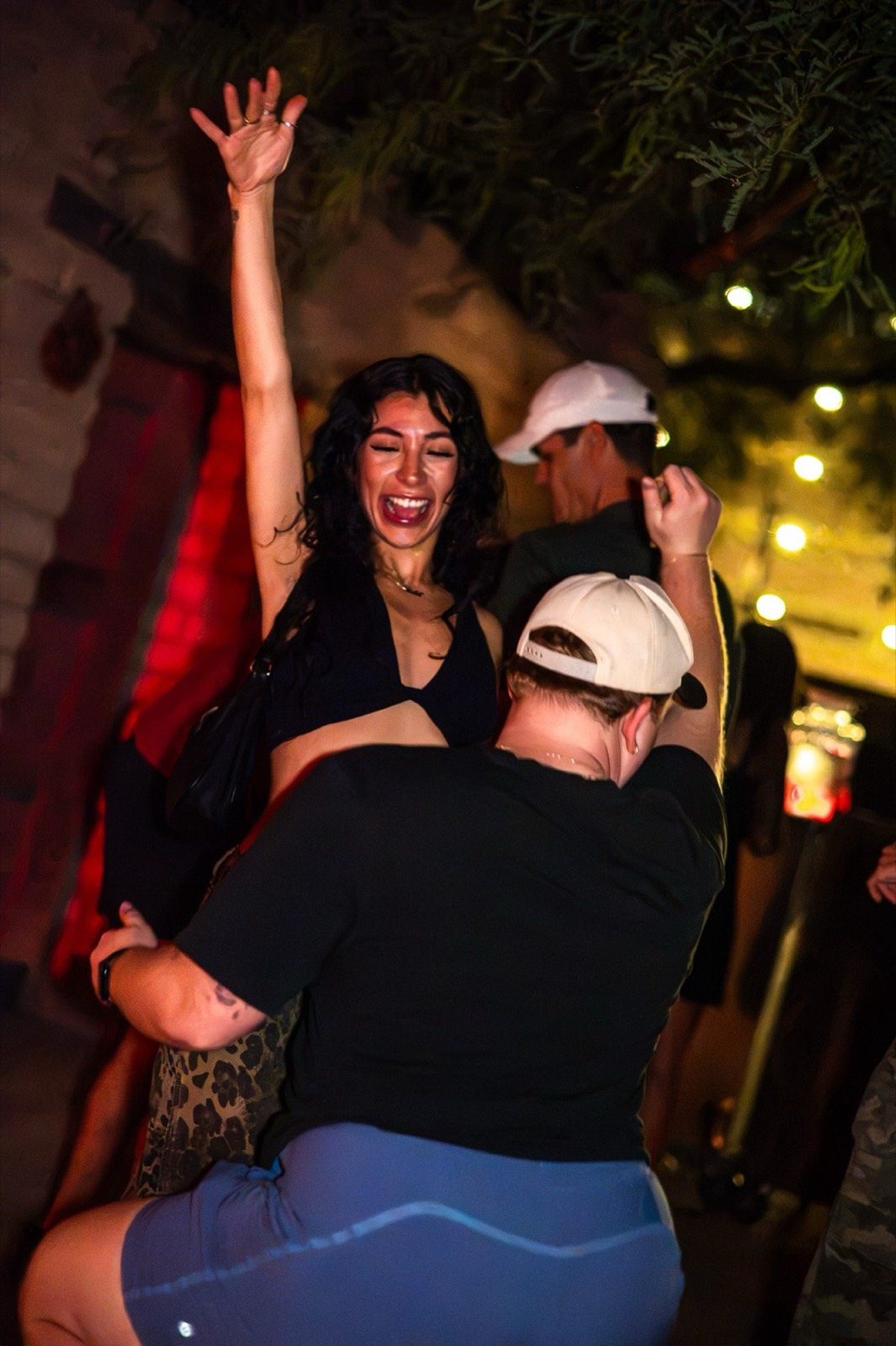 Two guests dancing, one arm raised, at a party in the courtyard