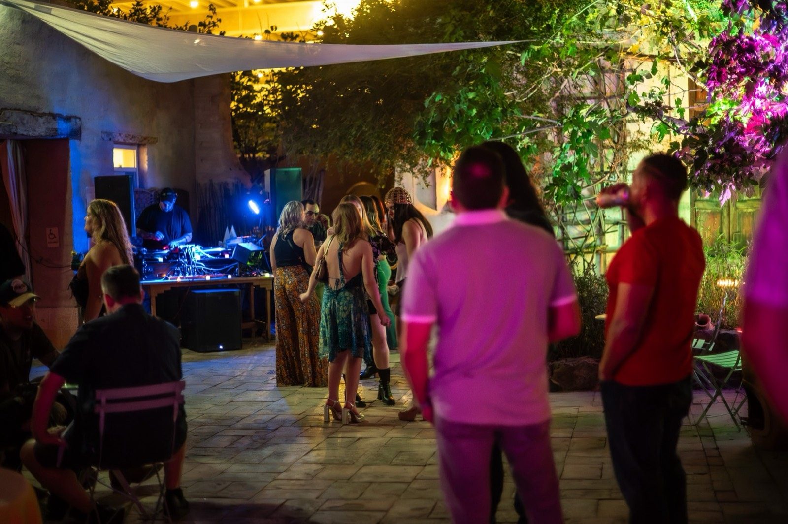 A nighttime patio party with a DJ, string lights and a lively crowd