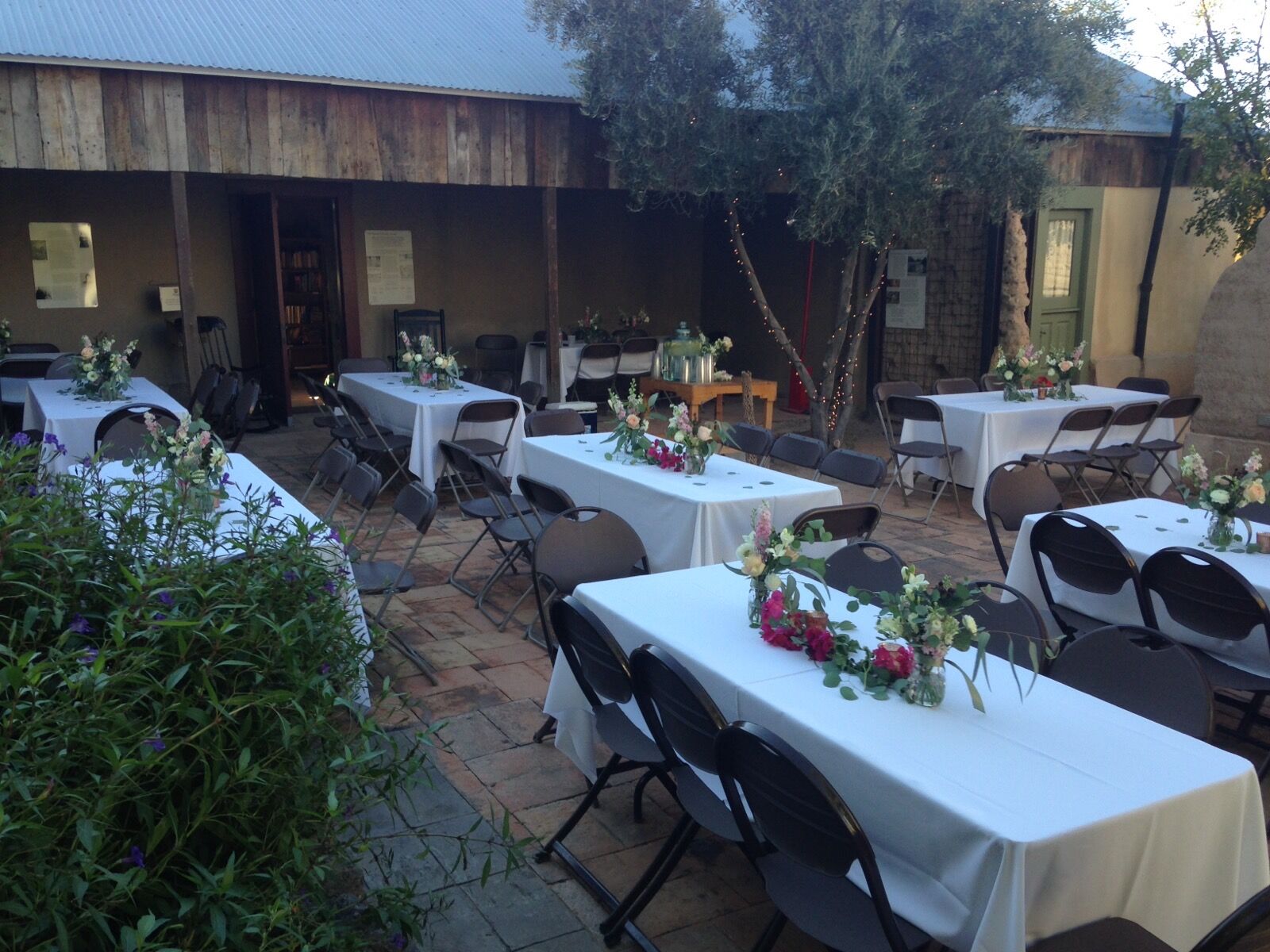 Long tables dressed in white linen and flowers in the courtyard