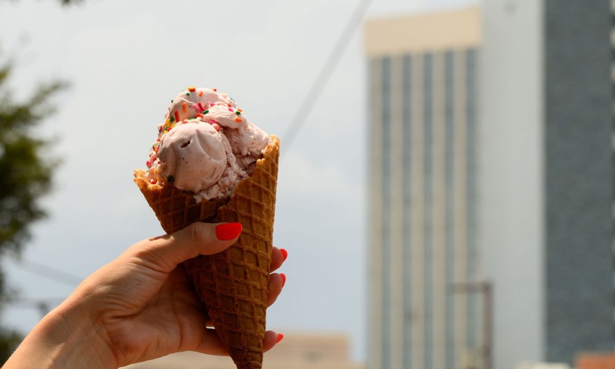 A waffle cone of strawberry ice cream held up against downtown Tucson towers