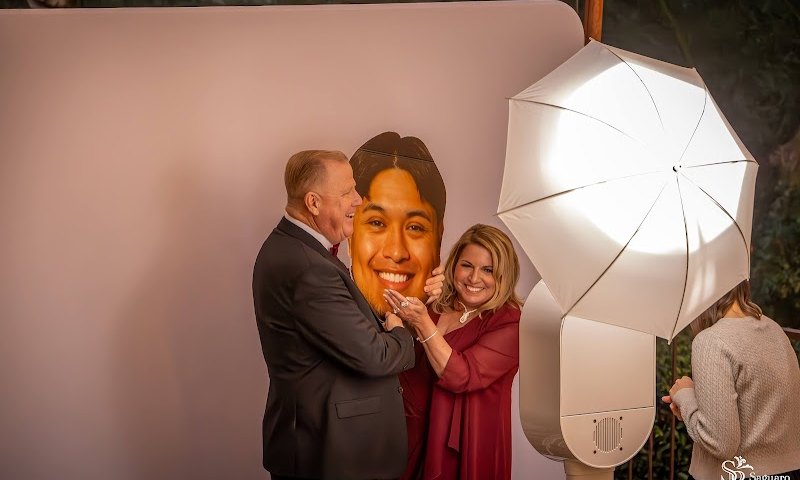 Wedding guests posing at a white photo booth with a softbox umbrella